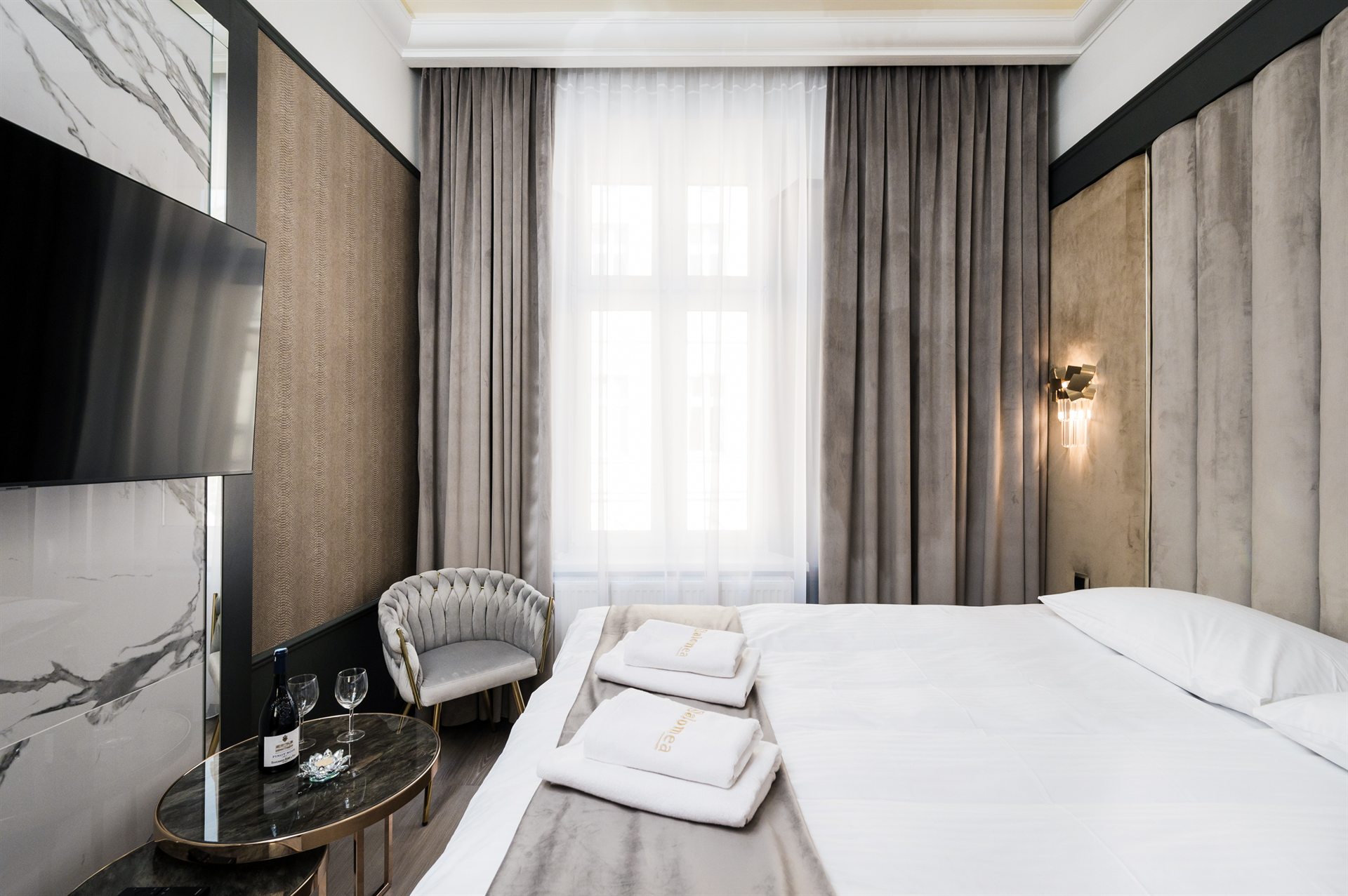 Elegancka sypialnia z dużym łóżkiem, telewizorem i szarymi zasłonami