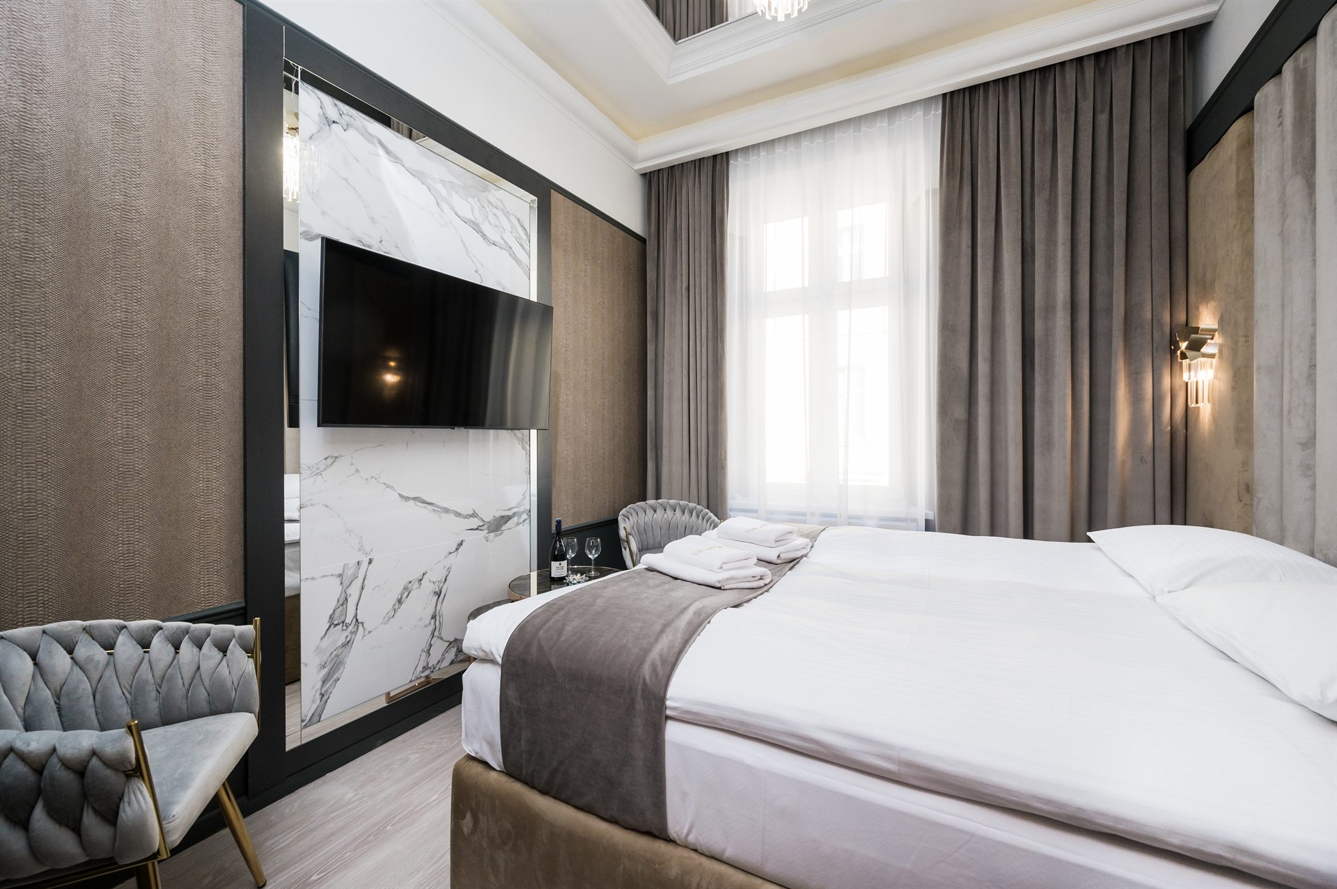 Stylowa, nowoczesna sypialnia z dużym łóżkiem i telewizorem na ścianie