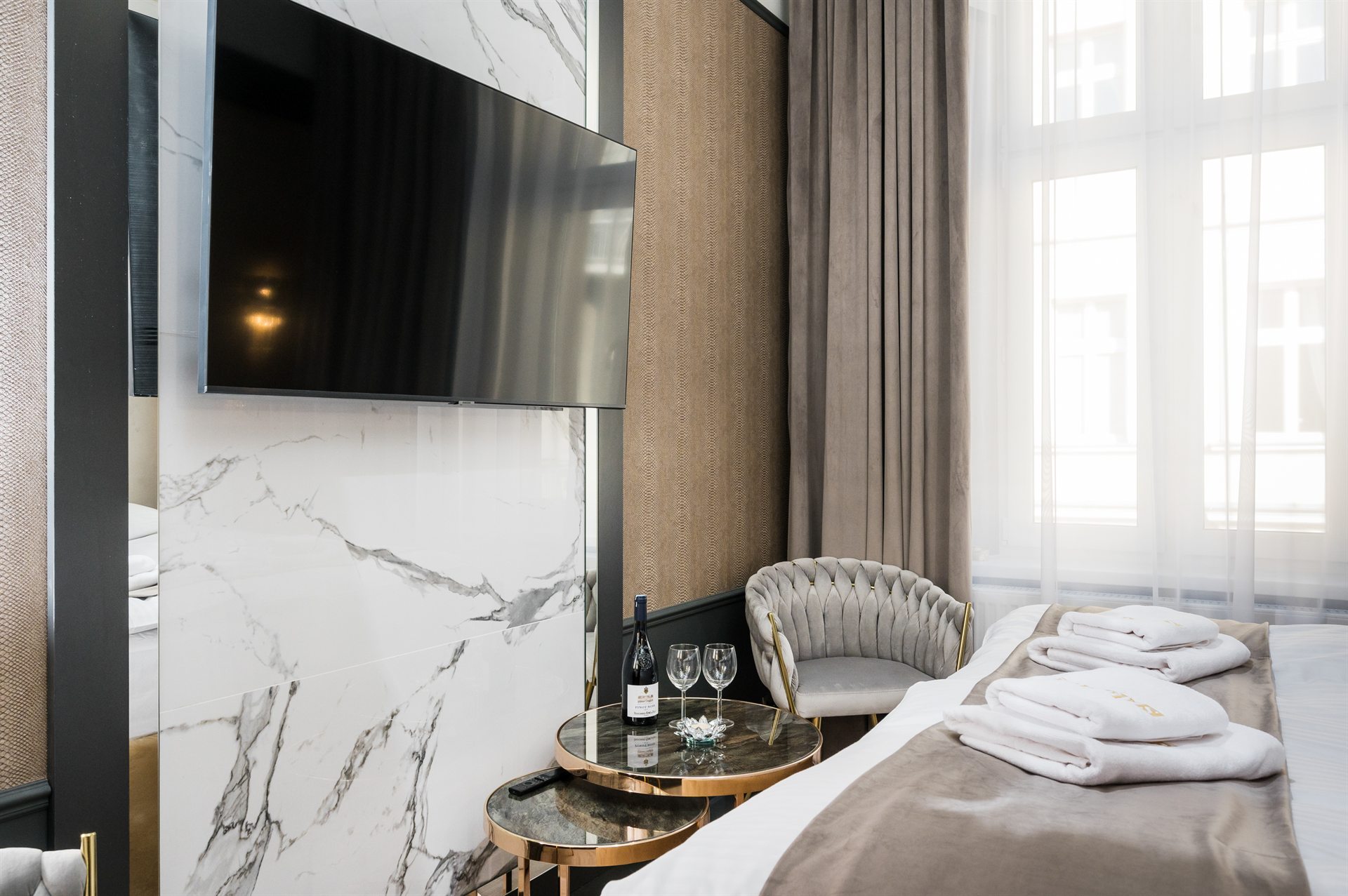 Stylowe wnętrze z telewizorem, eleganckim fotelem i kieliszkami wina