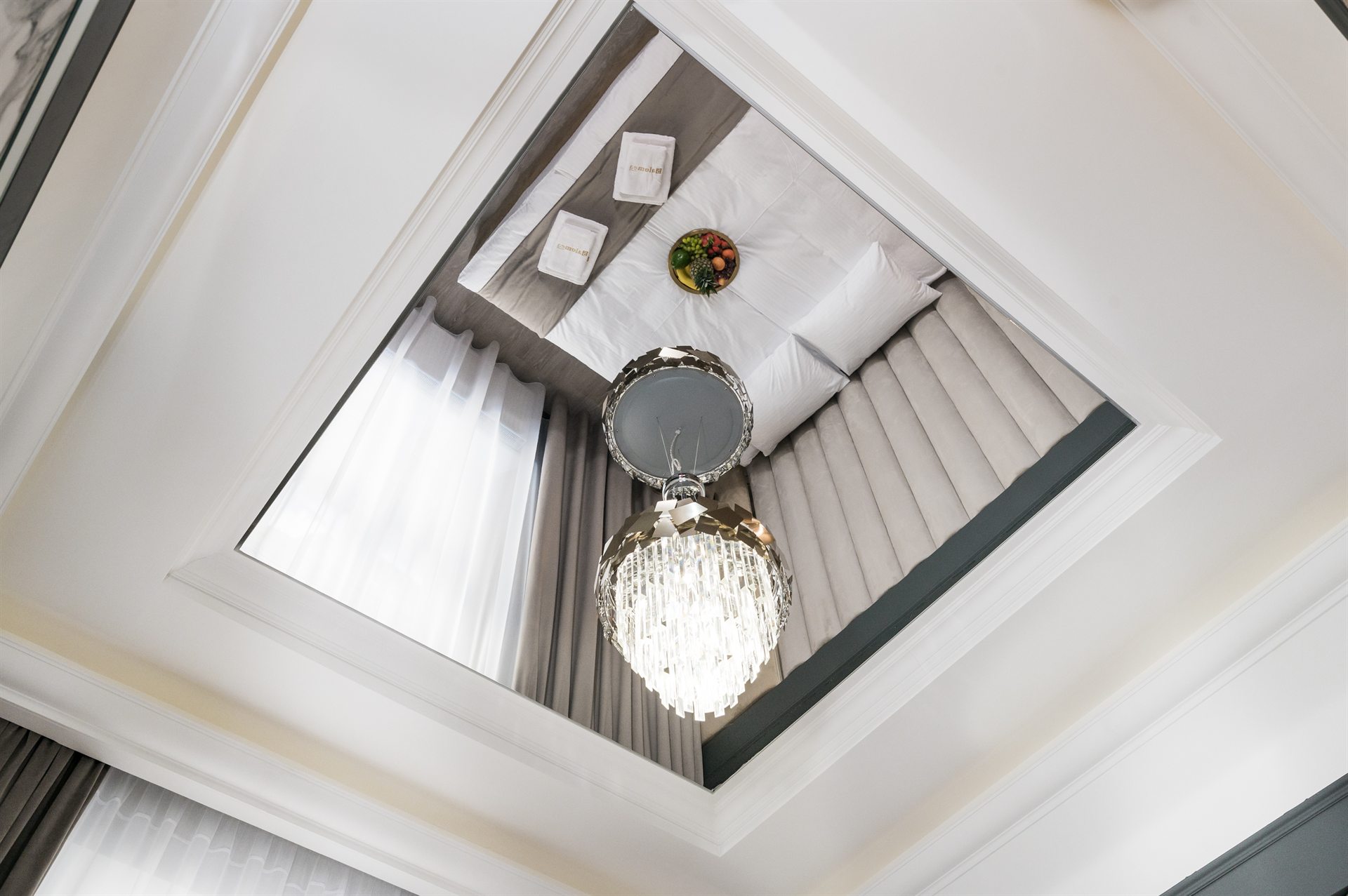 Elegancki sufit z żyrandolem, białe firany i łóżko z poduszkami