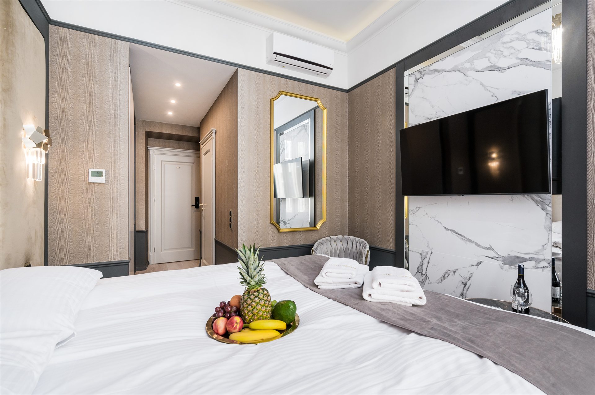 Stylowe wnętrze pokoju hotelowego z owocami na łóżku i telewizorem na ścianie