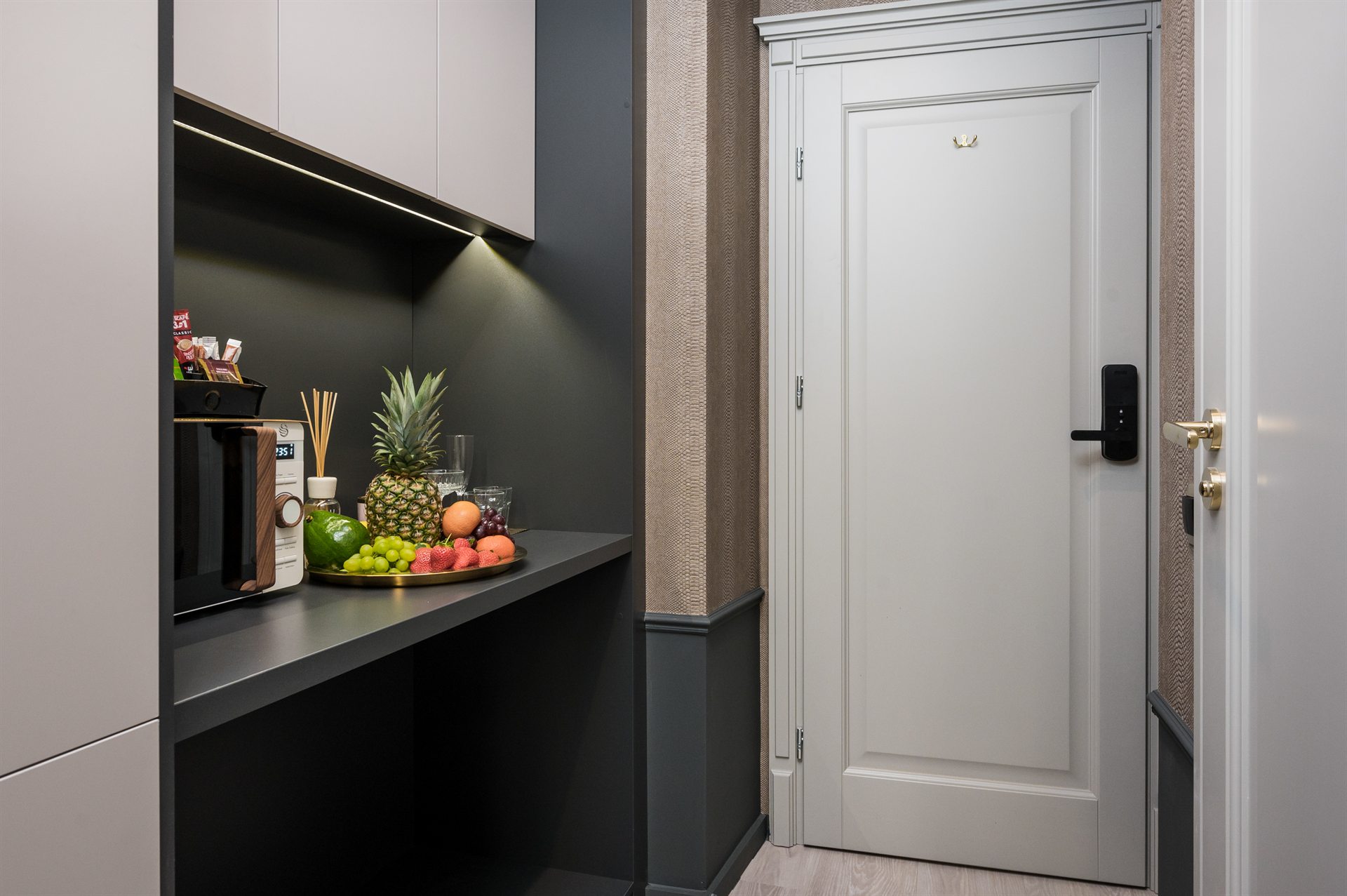 Kącik kuchenny z owocami, mikrofalówką i elegancką drzwiami wejściowymi