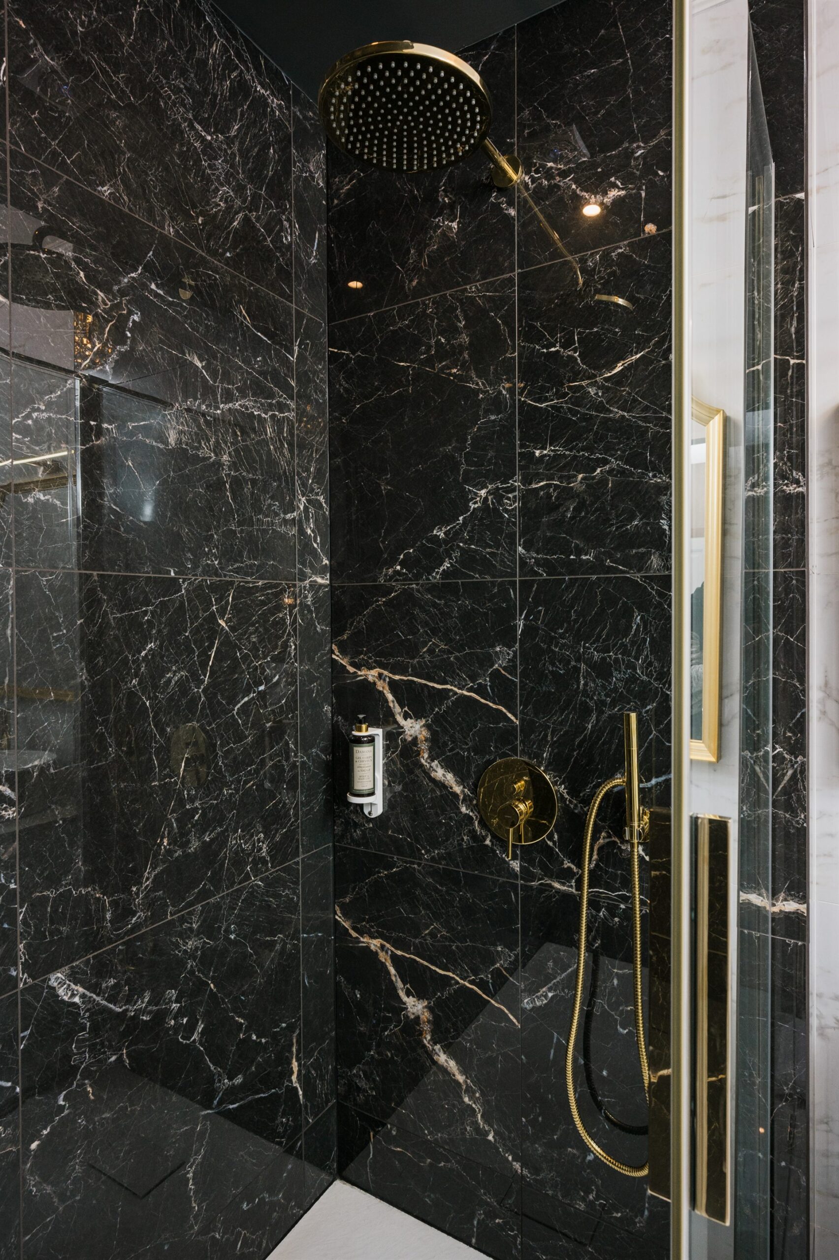 Kabina prysznicowa z czarnym marmurem i złotymi elementami wykończenia
