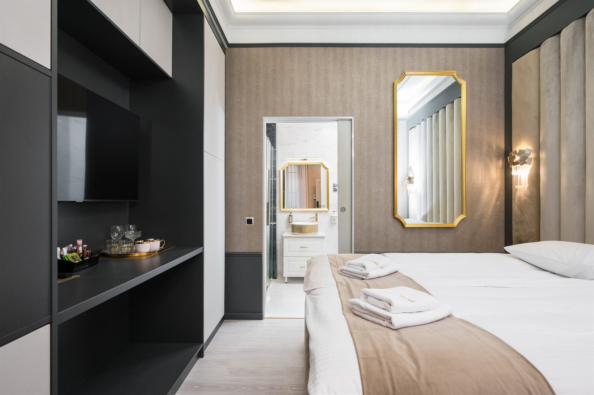 Nowoczesna sypialnia z łóżkiem, lustrem w złotej ramie i dużym telewizorem