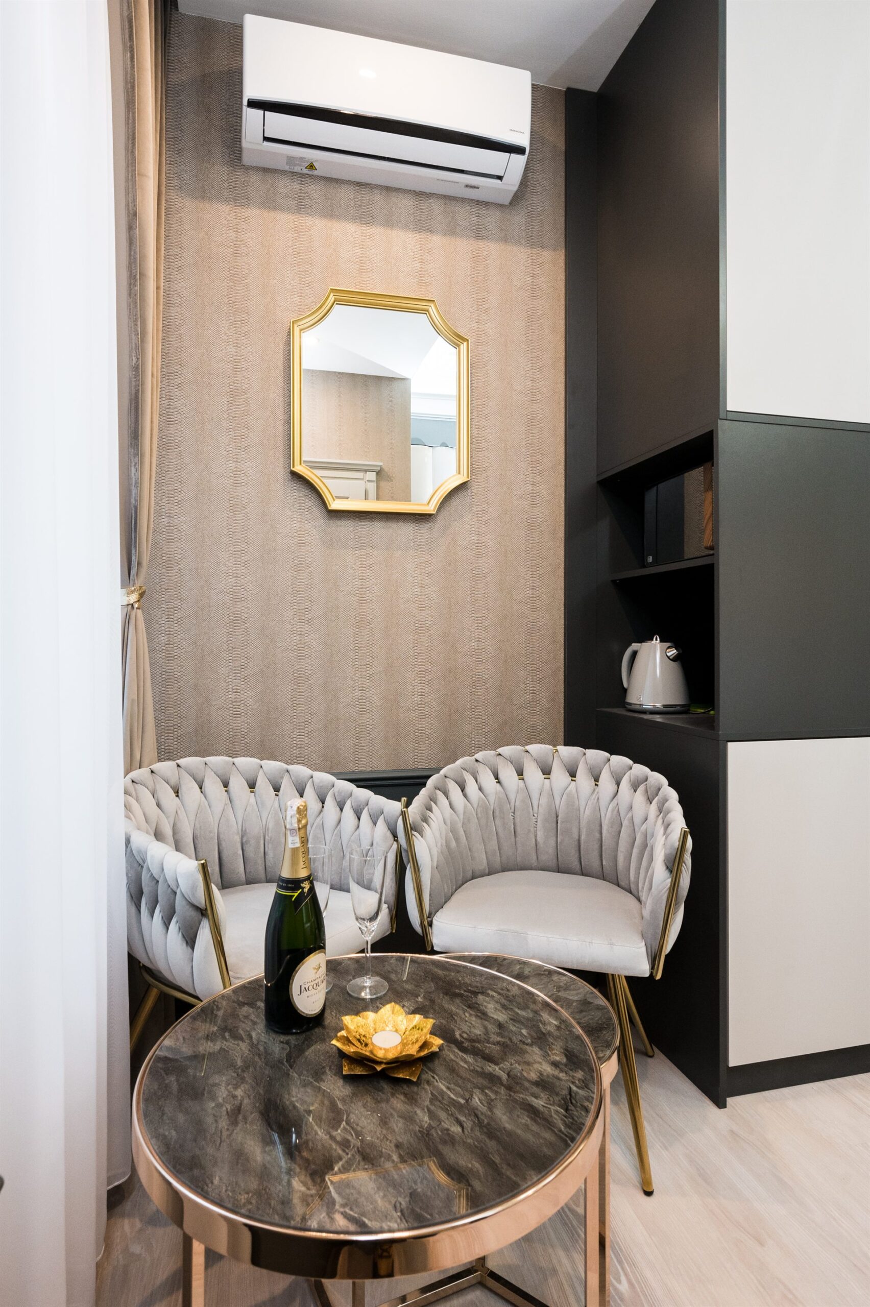 Elegancki kącik z szarymi fotelami, okrągłym stolikiem i szampanem
