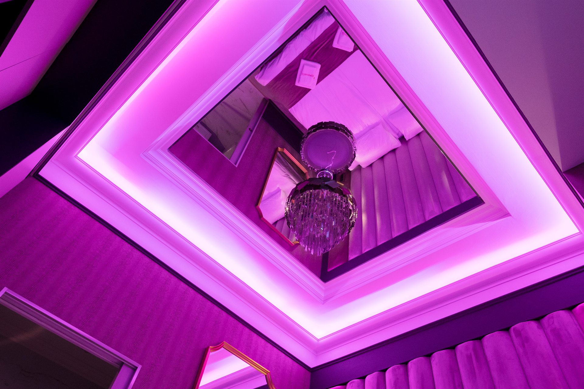 Sufit z oświetleniem LED w odcieniach fioletu i kryształowym żyrandolem