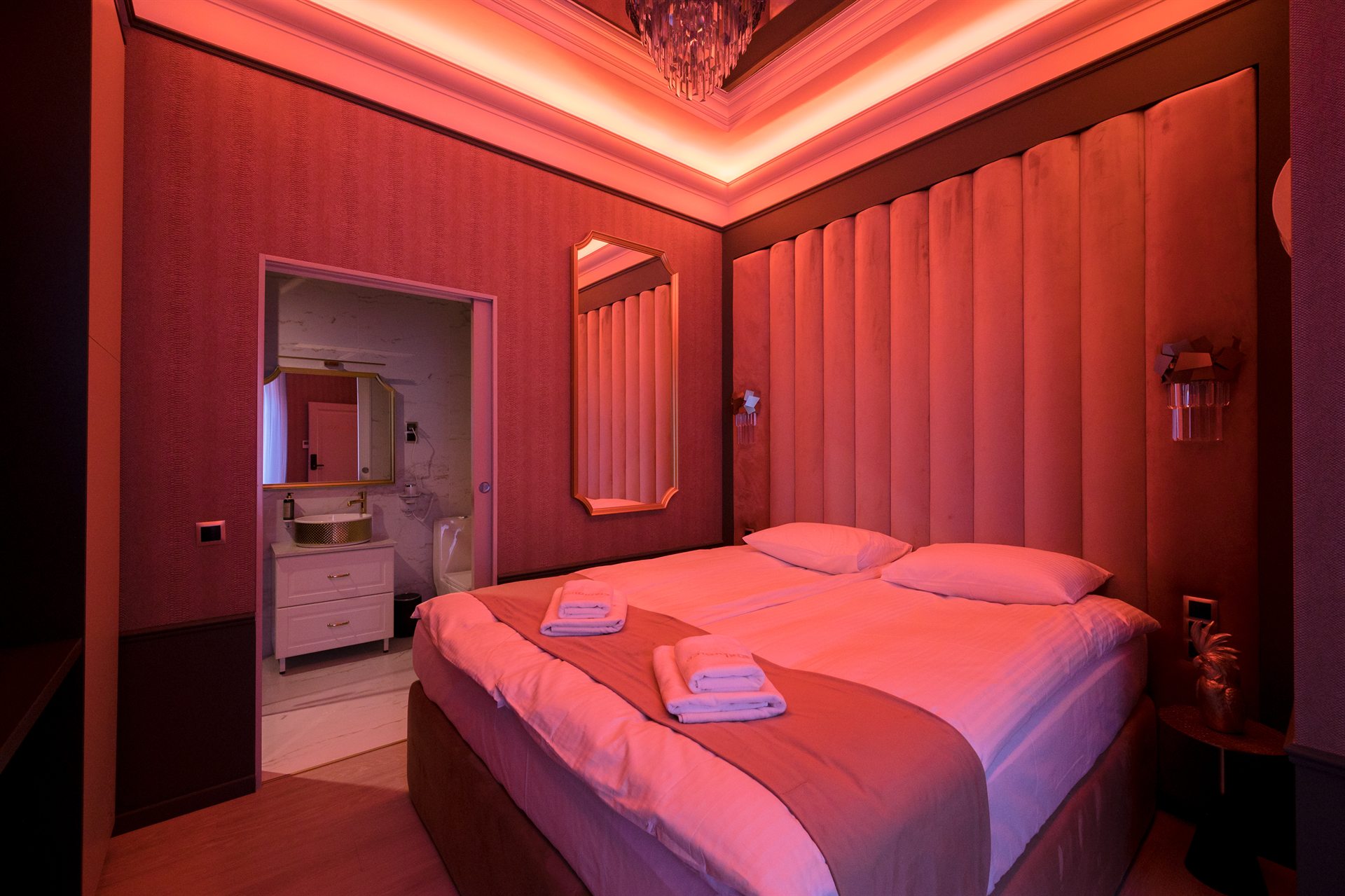Stylowa sypialnia z różowym oświetleniem i podwójnym łóżkiem
