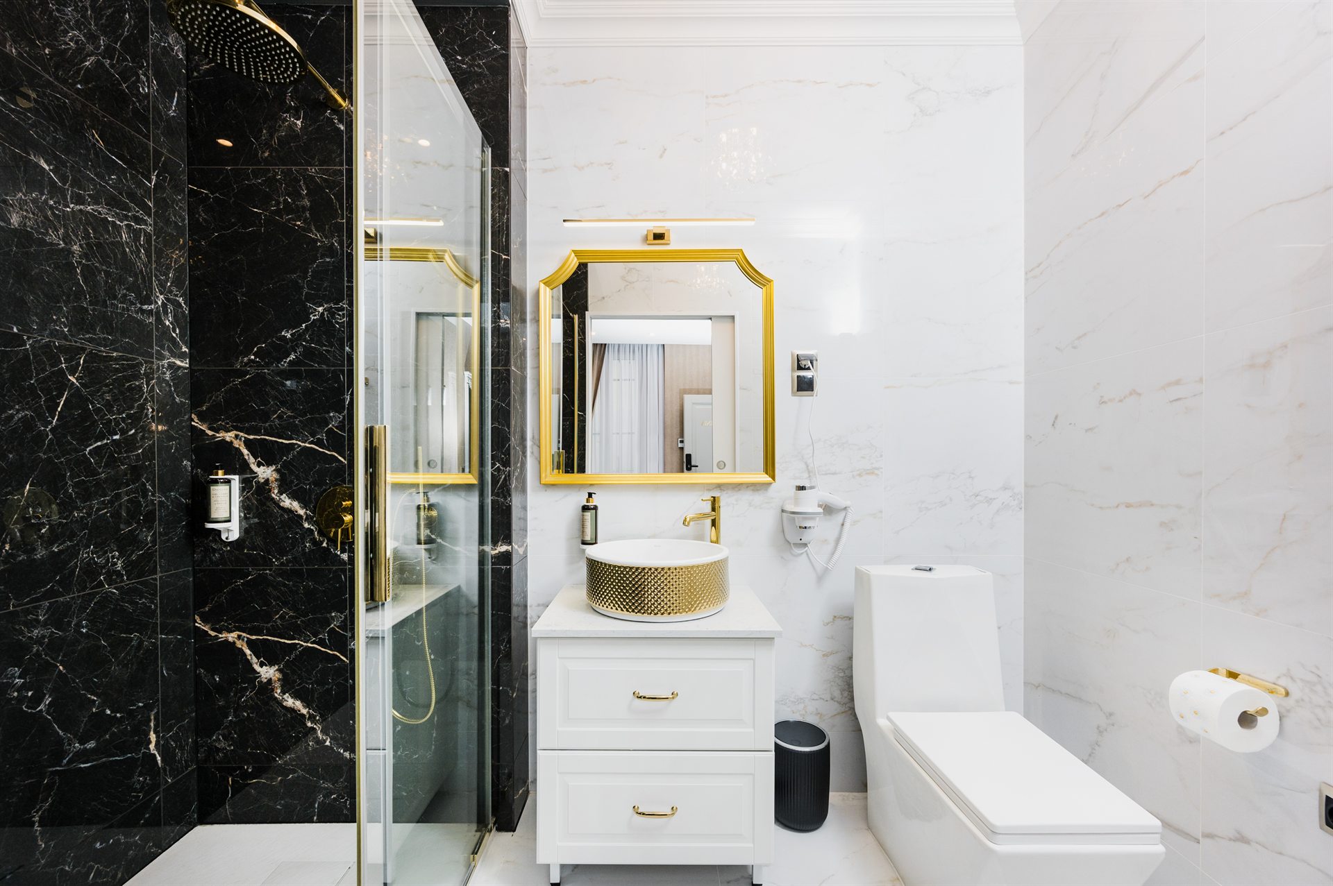 Elegancka łazienka z czarnym marmurem, złotymi akcentami i lustrem