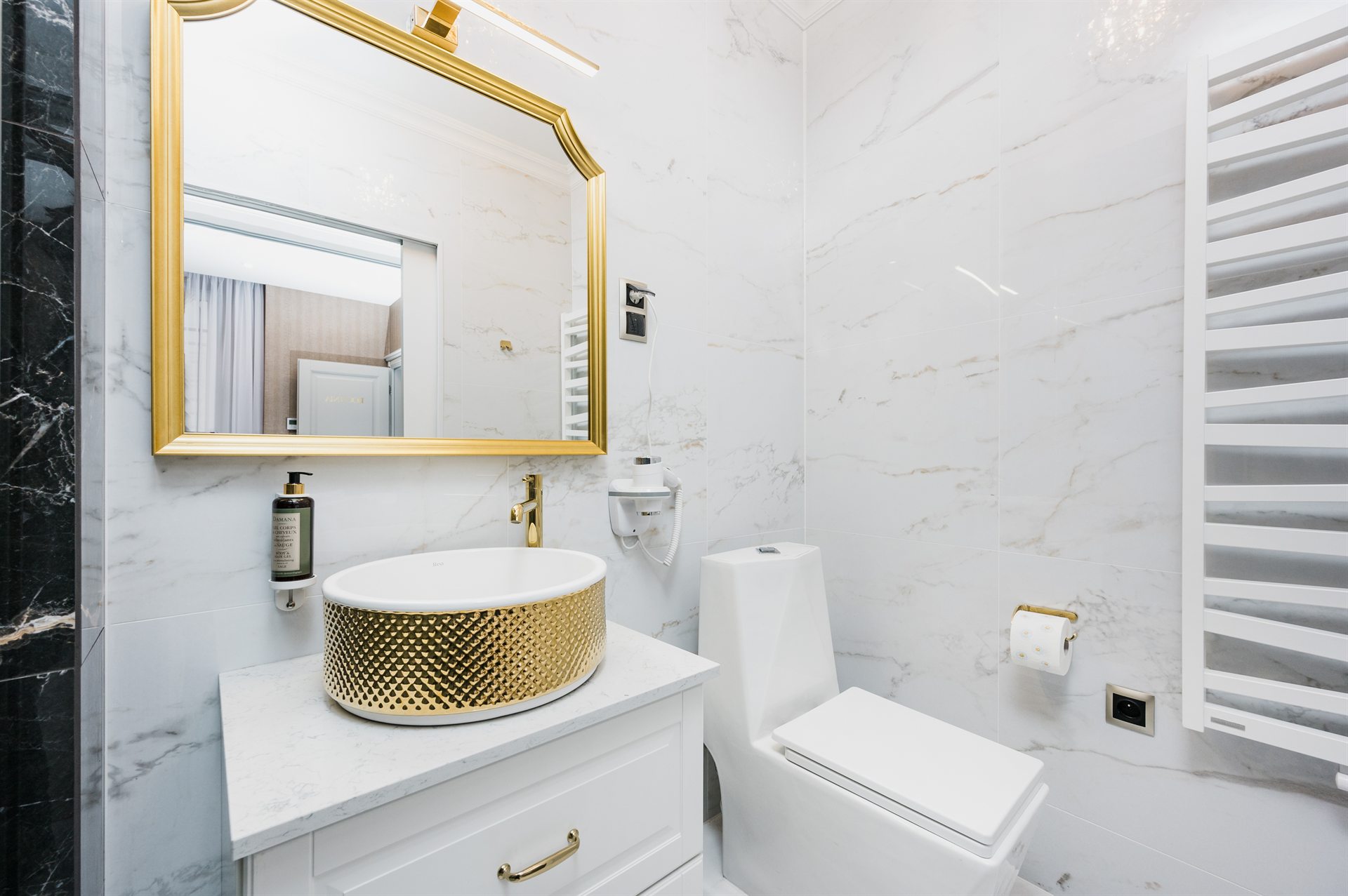 Elegancka łazienka z marmurowymi płytkami, złotym lustrem i umywalką