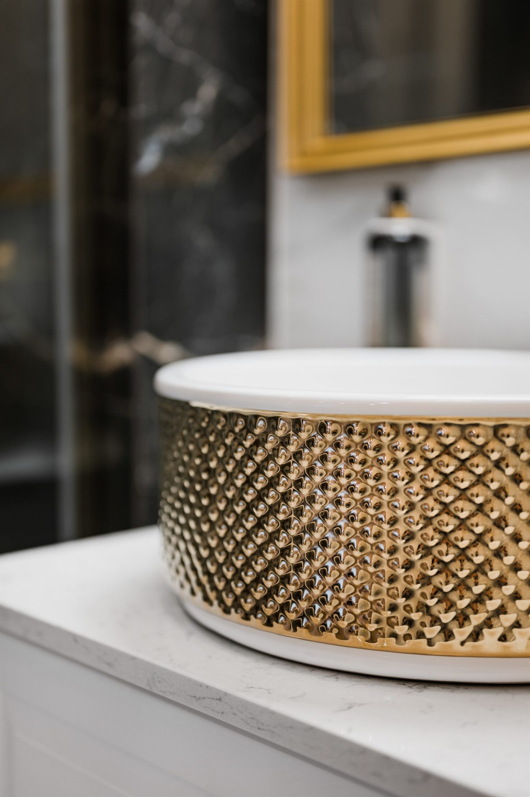 Okrągła umywalka z ozdobnym, złotym wykończeniem na białym blacie