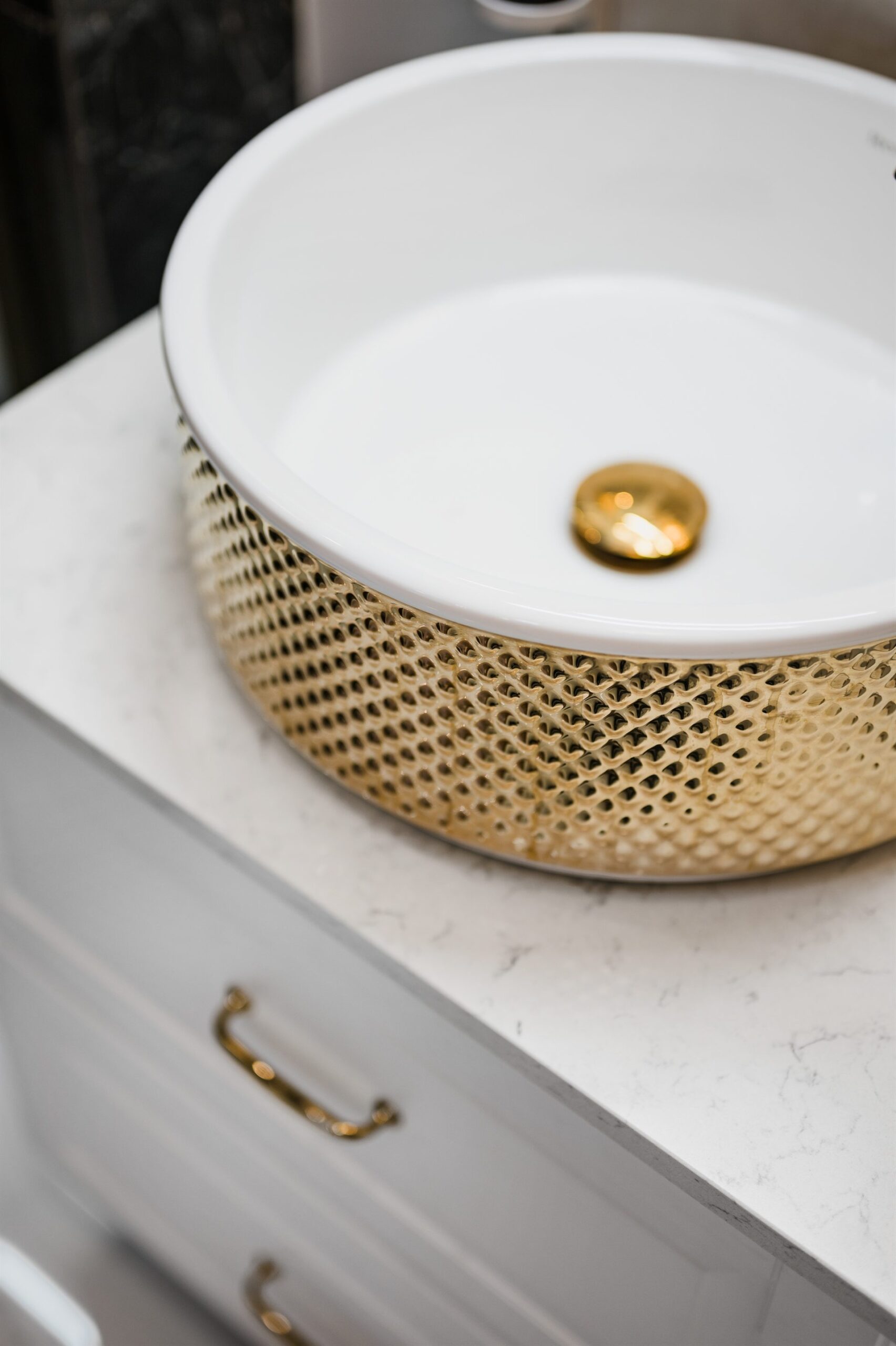 Biała umywalka na stylowym złotym stelażu, na marmurowym blacie