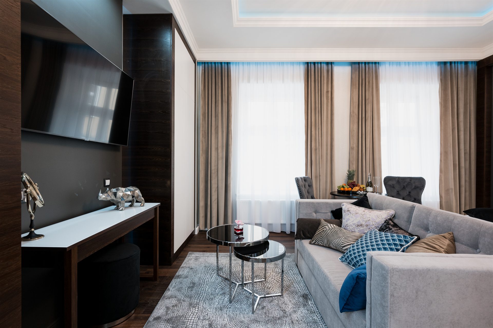 Elegancki salon z szarym sofą, dużym telewizorem i stylowymi dodatkami