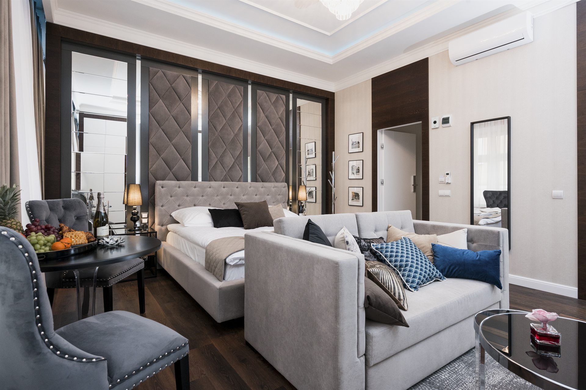 Elegancka sypialnia z podwójnym łóżkiem, sofą i stołem z owocami