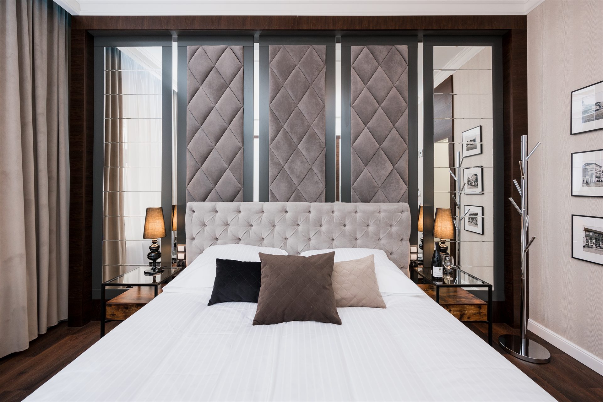 Stylowa sypialnia z eleganckim łóżkiem, poduszkami i lustrzanymi akcentami