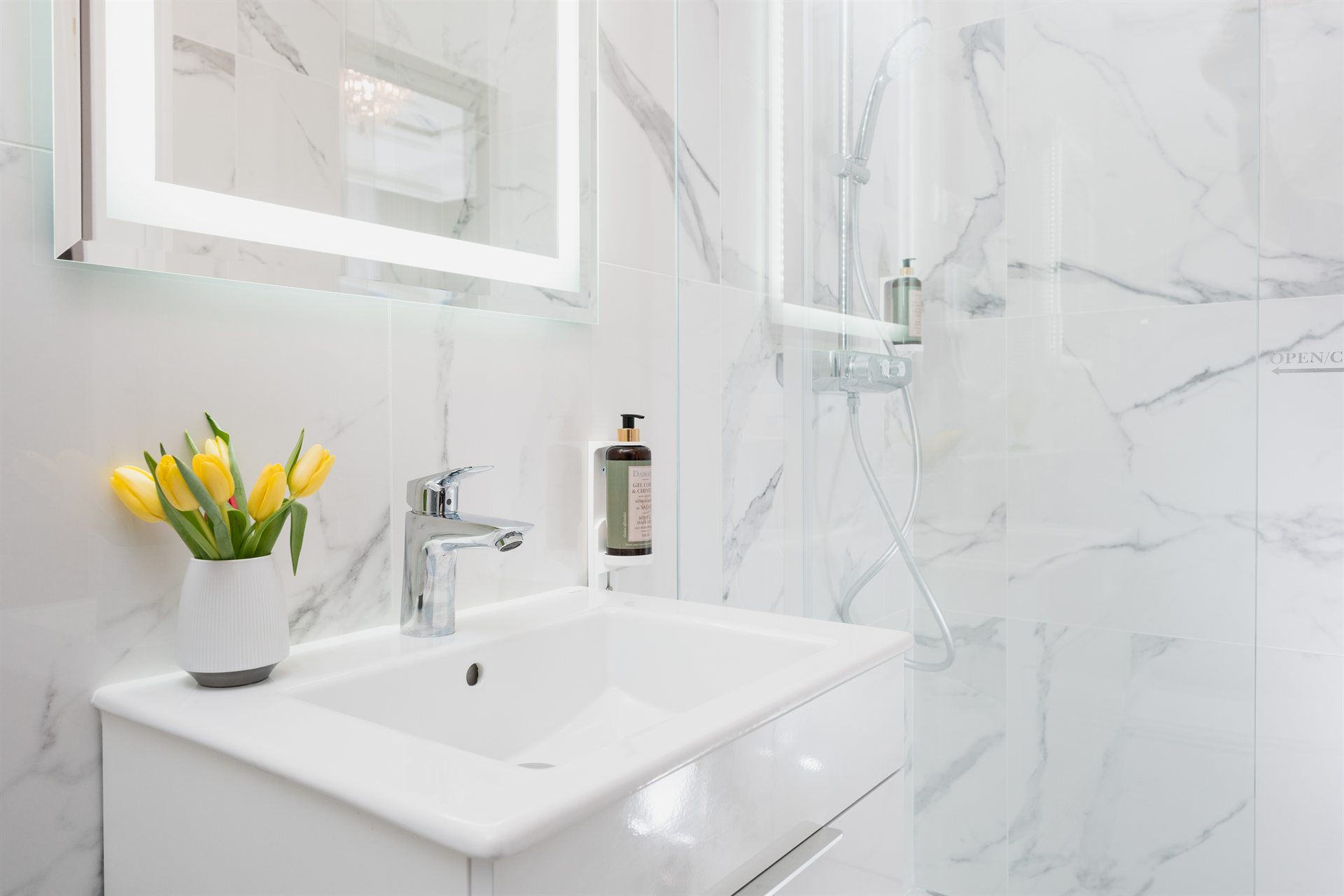 Nowoczesna łazienka z umywalką, kwiatami i lustrzanym oświetleniem