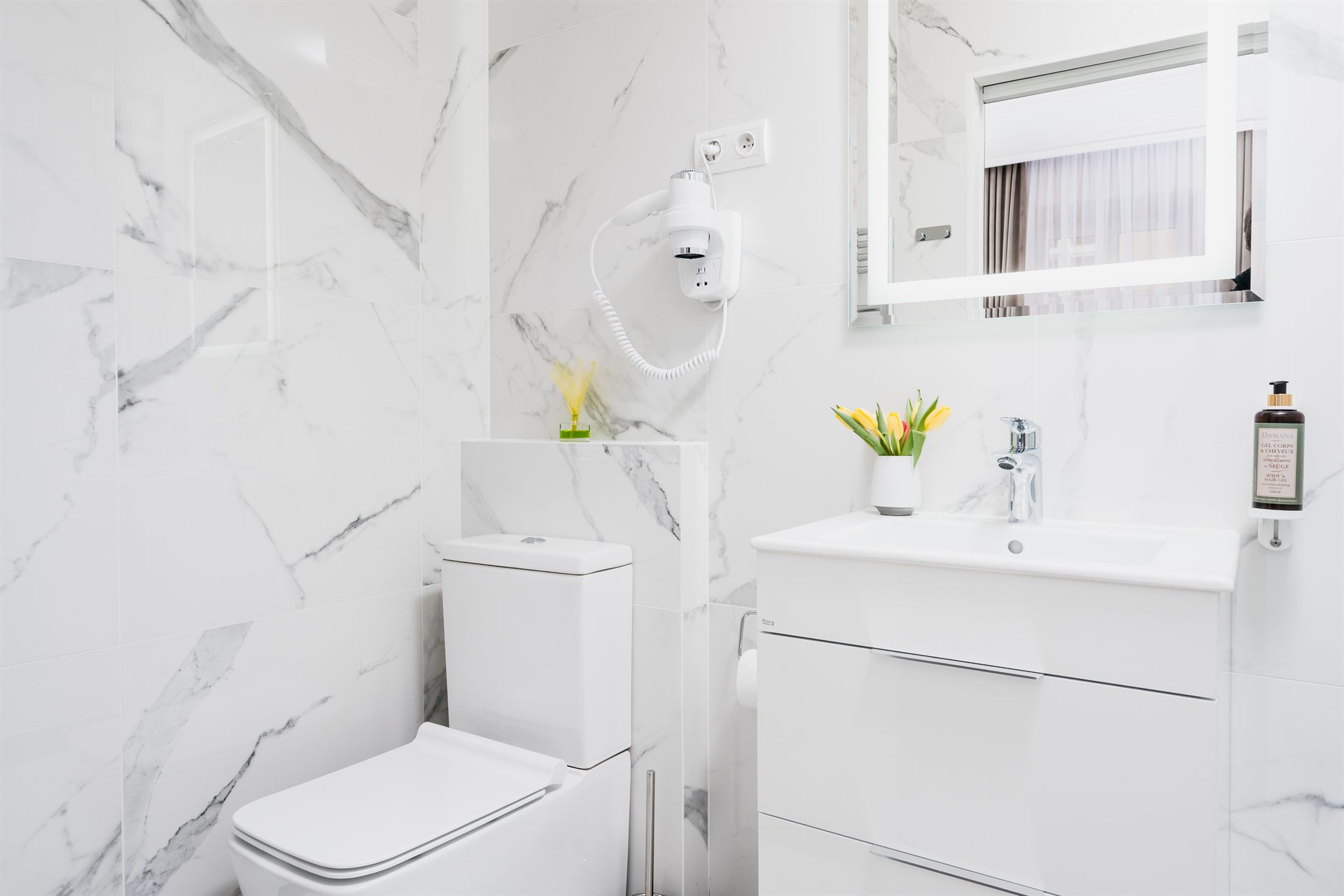 Nowoczesna łazienka z białymi płytkami marmurowymi, umywalką i roślinami