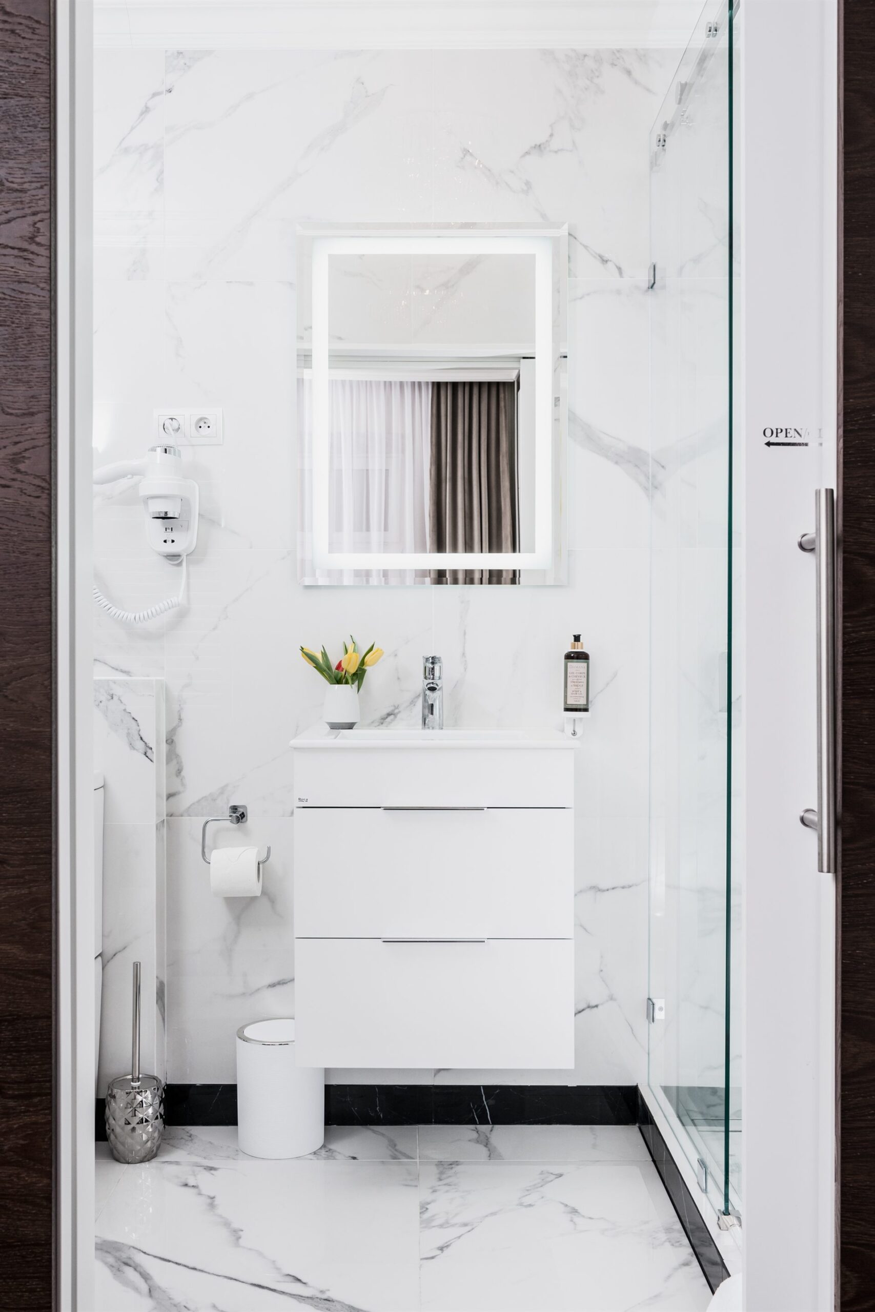 Nowoczesna łazienka z białymi kafelkami, prysznicem i umywalką z szafką