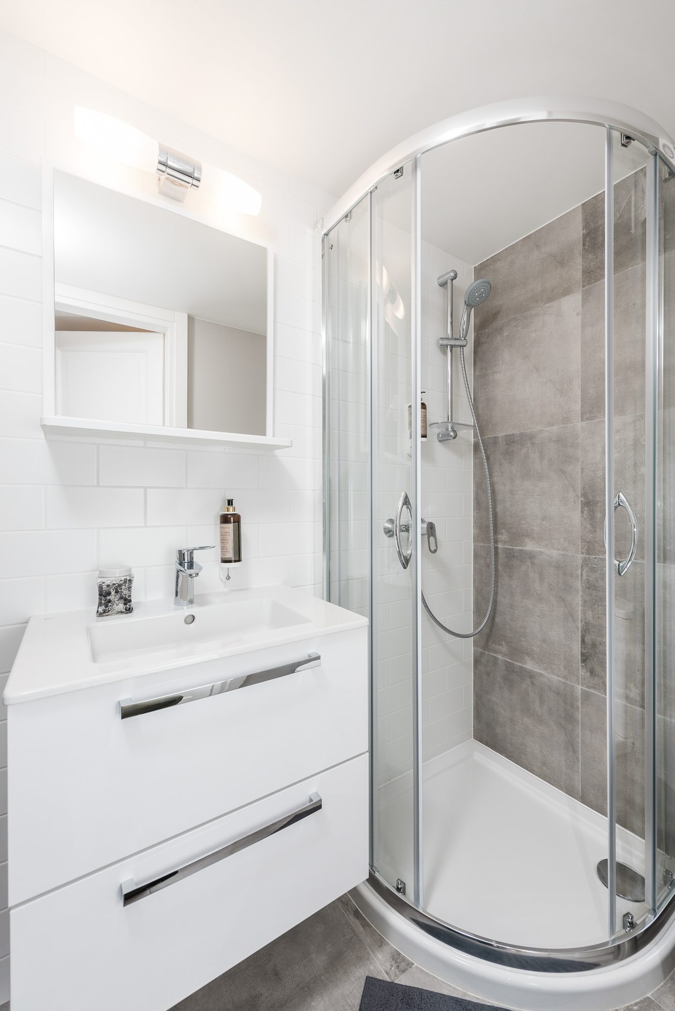 Nowoczesna łazienka z przeszkloną kabiną prysznicową i białą umywalką