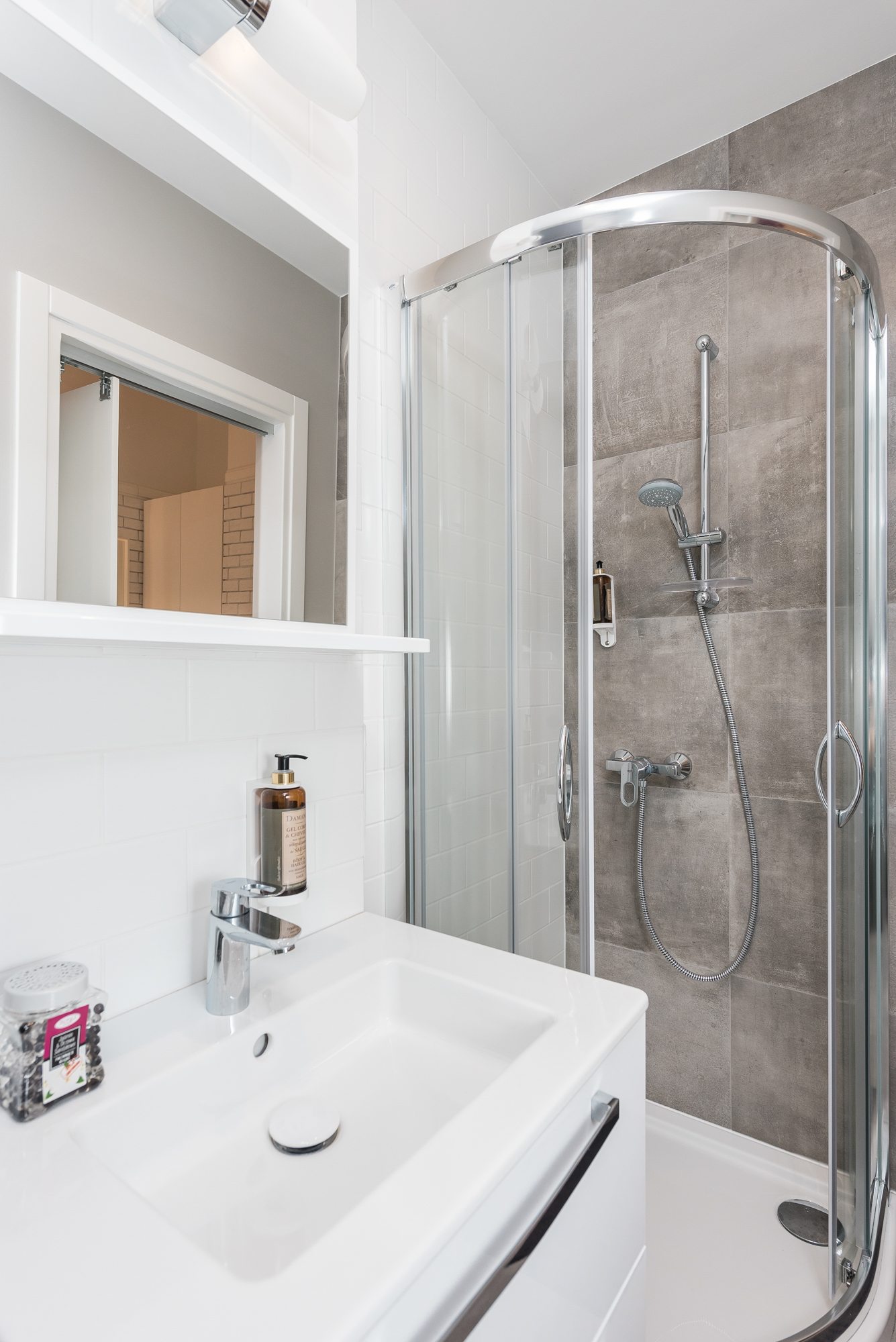 Nowoczesna łazienka z kabiną prysznicową, białą umywalką i lustrem