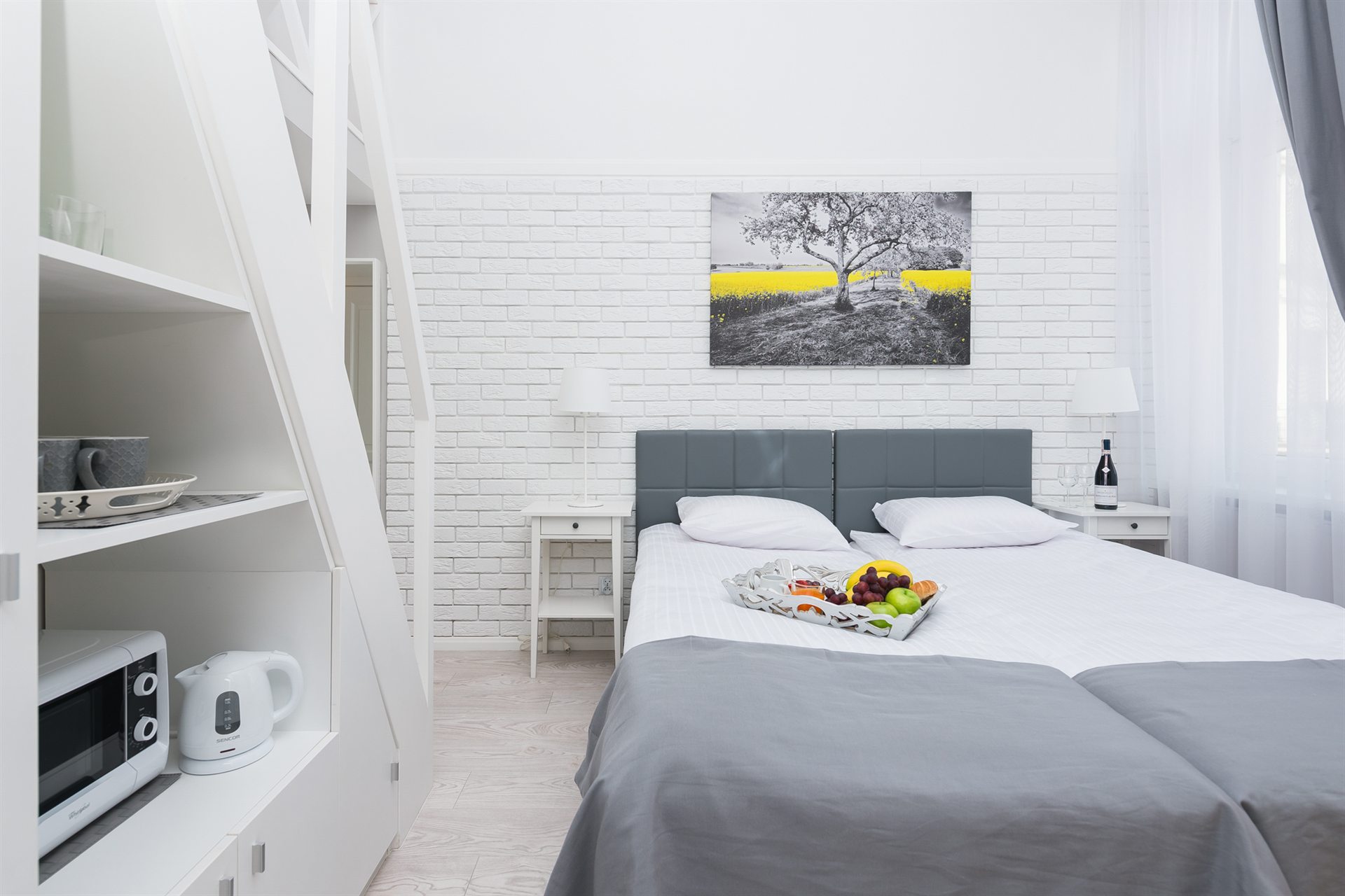 Nowoczesna sypialnia z dwoma łóżkami, białą ceglaną ścianą i owocami na talerzu