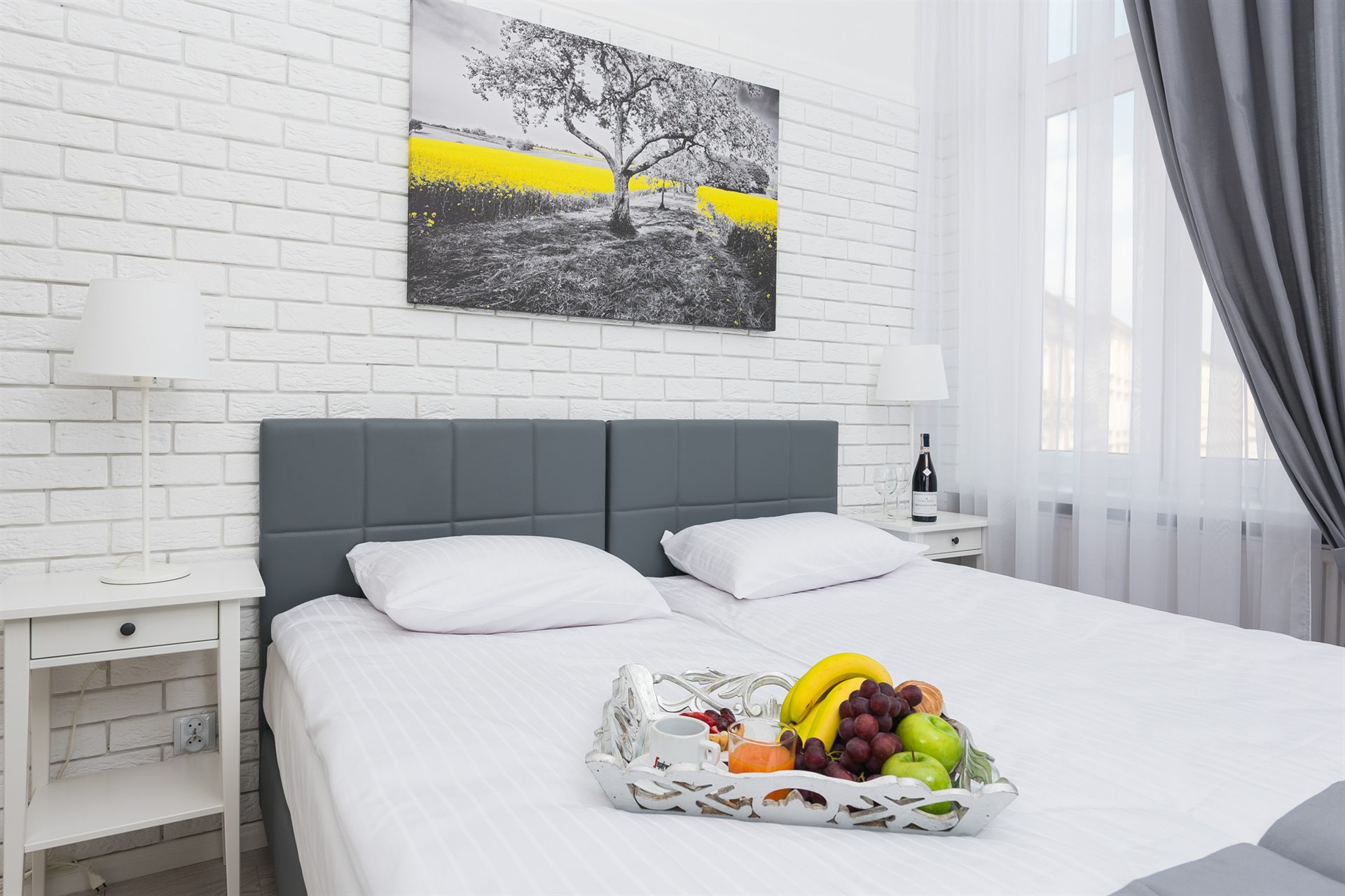 Sypialnia z białymi ścianami, szaro-zielonym łóżkiem i owocami w koszyku