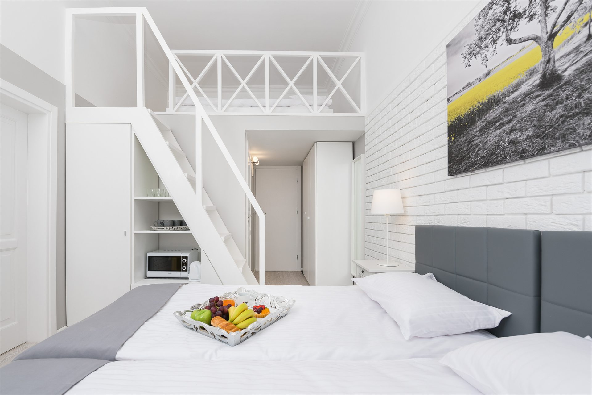 Nowoczesny pokój z antresolą, białymi ścianami i świeżymi owocami na łóżku