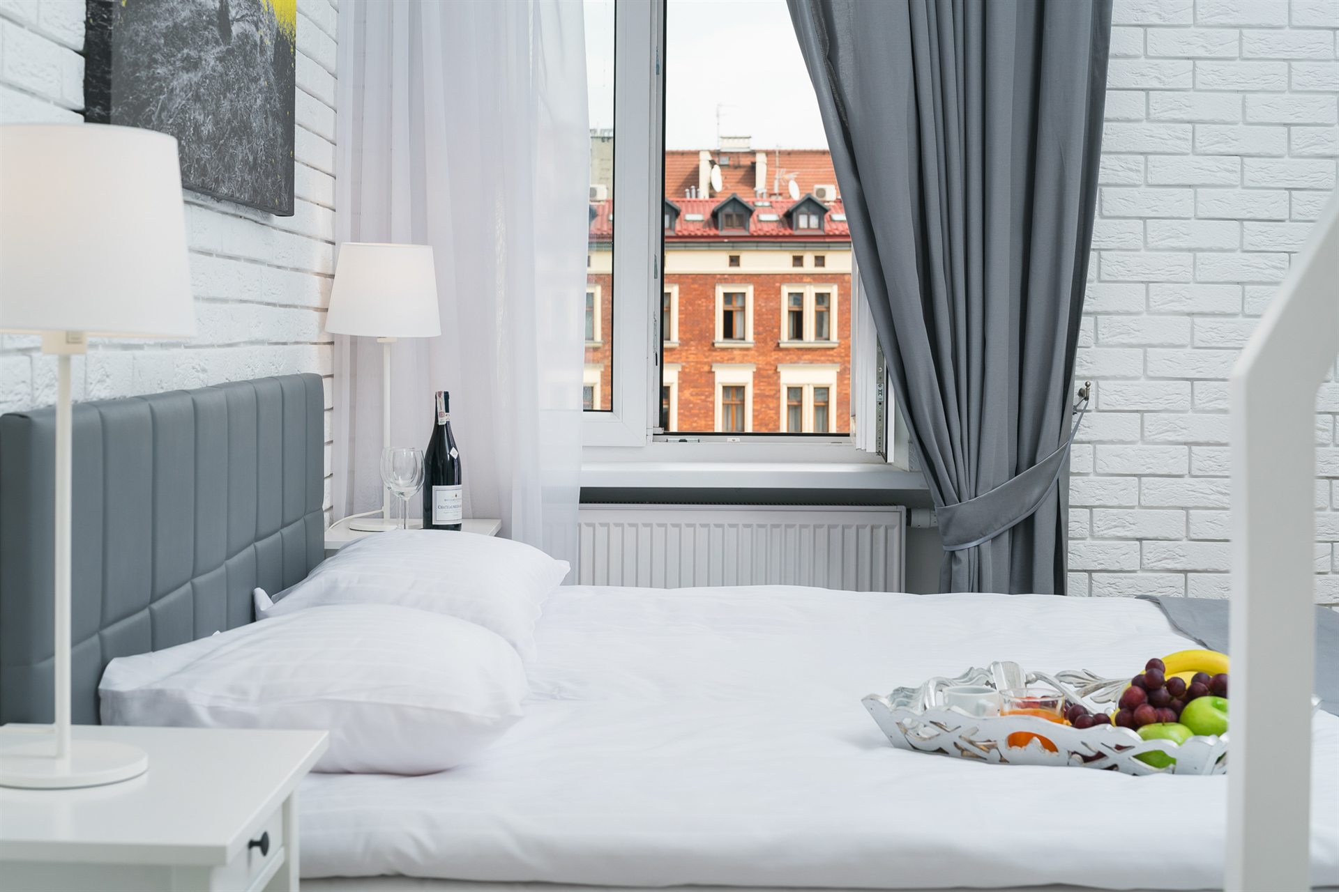 Stylowa sypialnia z białą cegłą, łóżkiem i widokiem na miasto przez okno