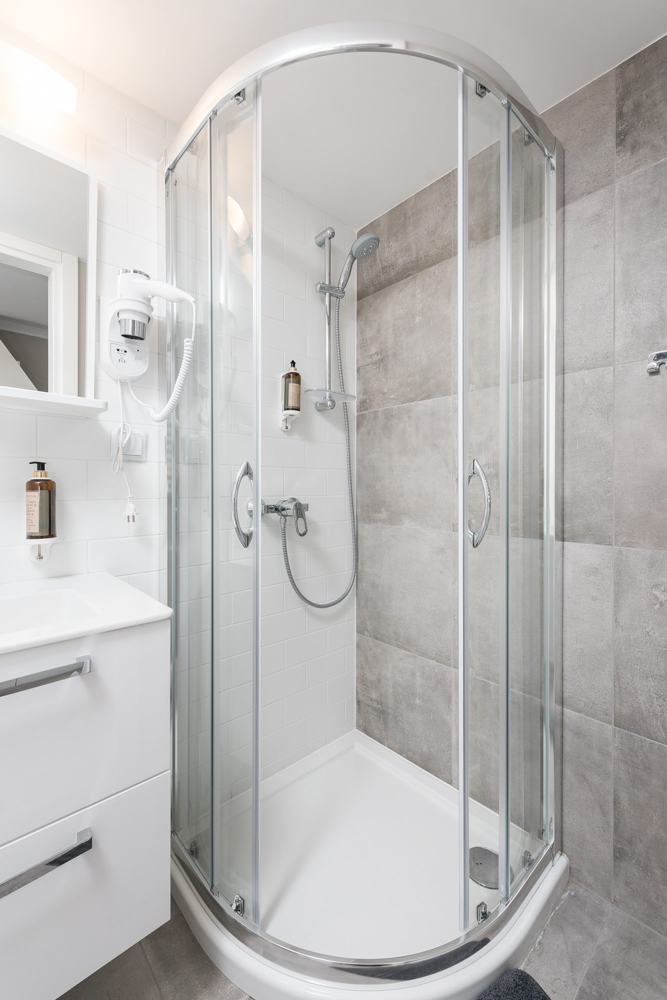 Kabina prysznicowa z przeszkleniem, białe płytki i szara ściana