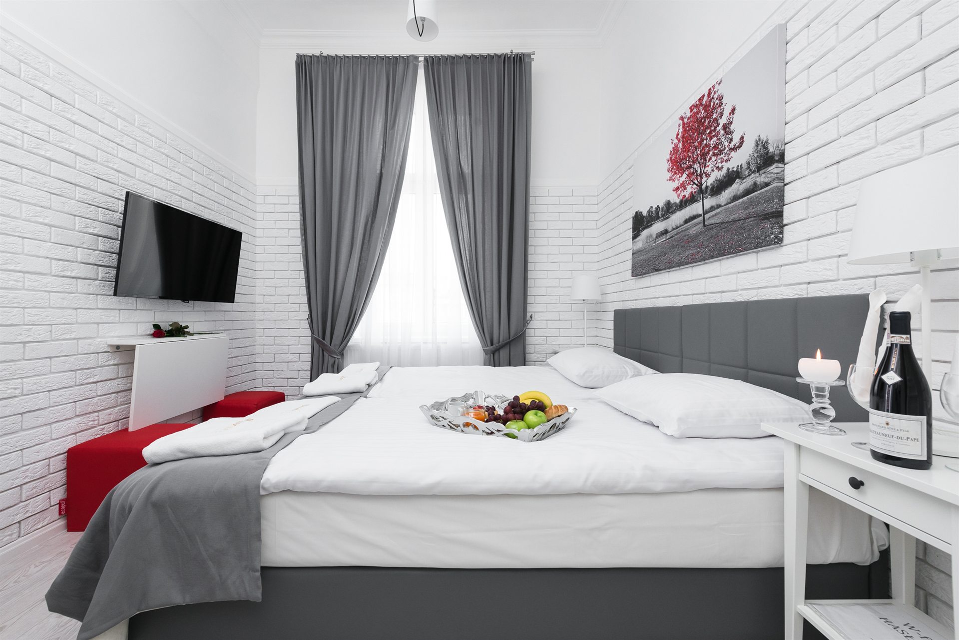 Nowoczesna sypialnia z dużym łóżkiem, szaro-białymi akcentami i owocami na stole