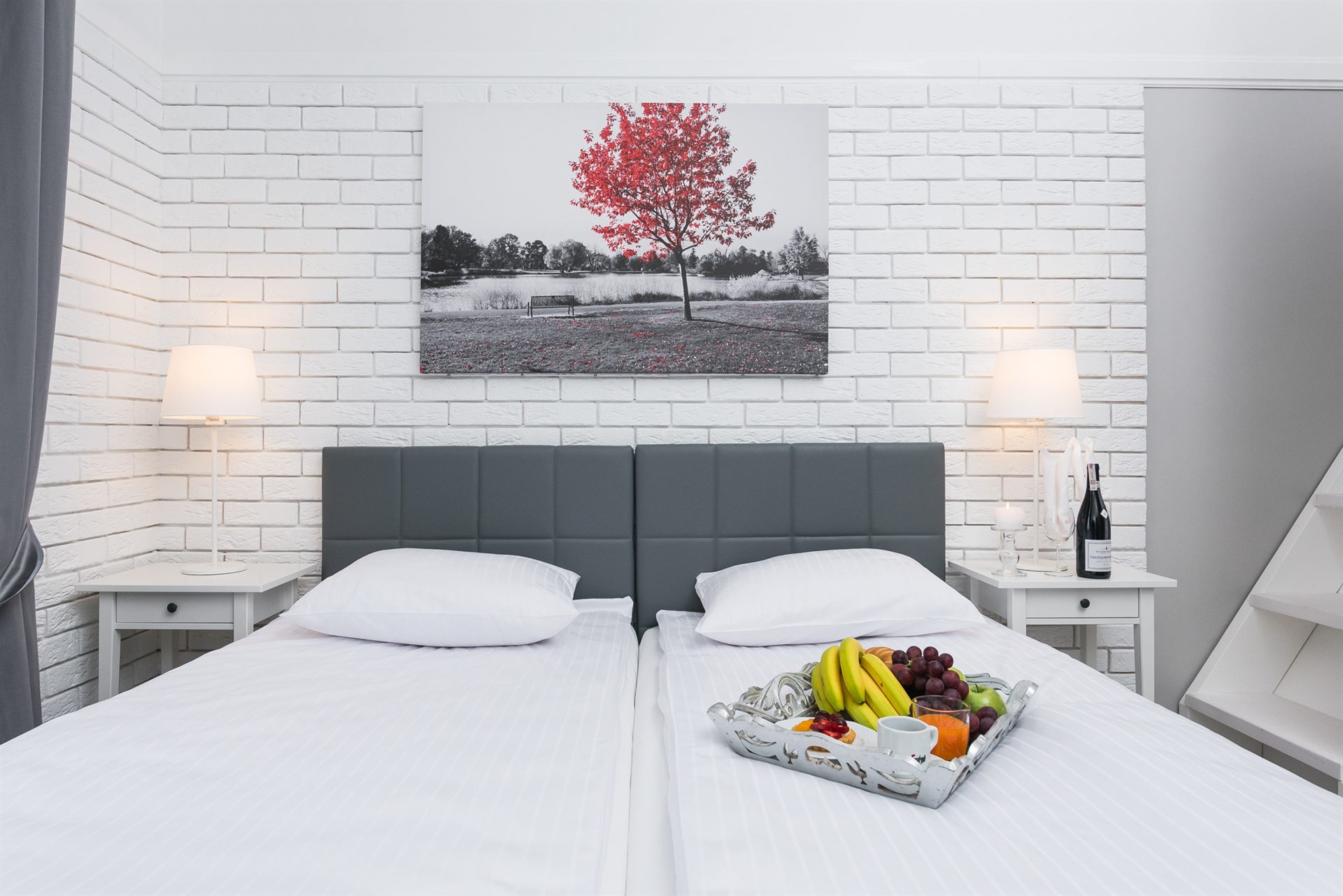 Dwa łóżka w eleganckim wnętrzu z obrazem czerwonego drzewa i owocami