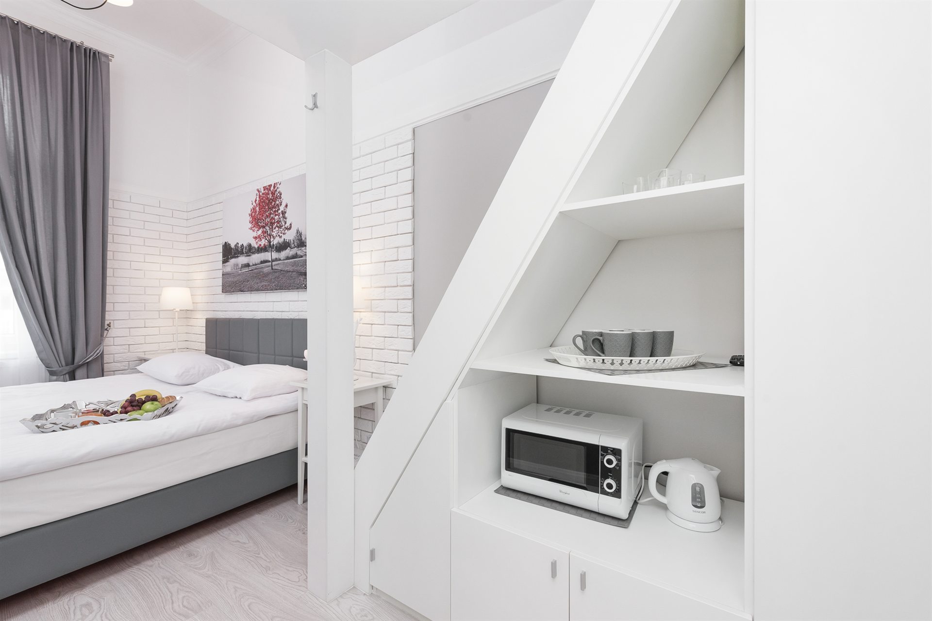 Nowoczesna sypialnia z łóżkiem, obrazem i sprzętem kuchennym w szafce