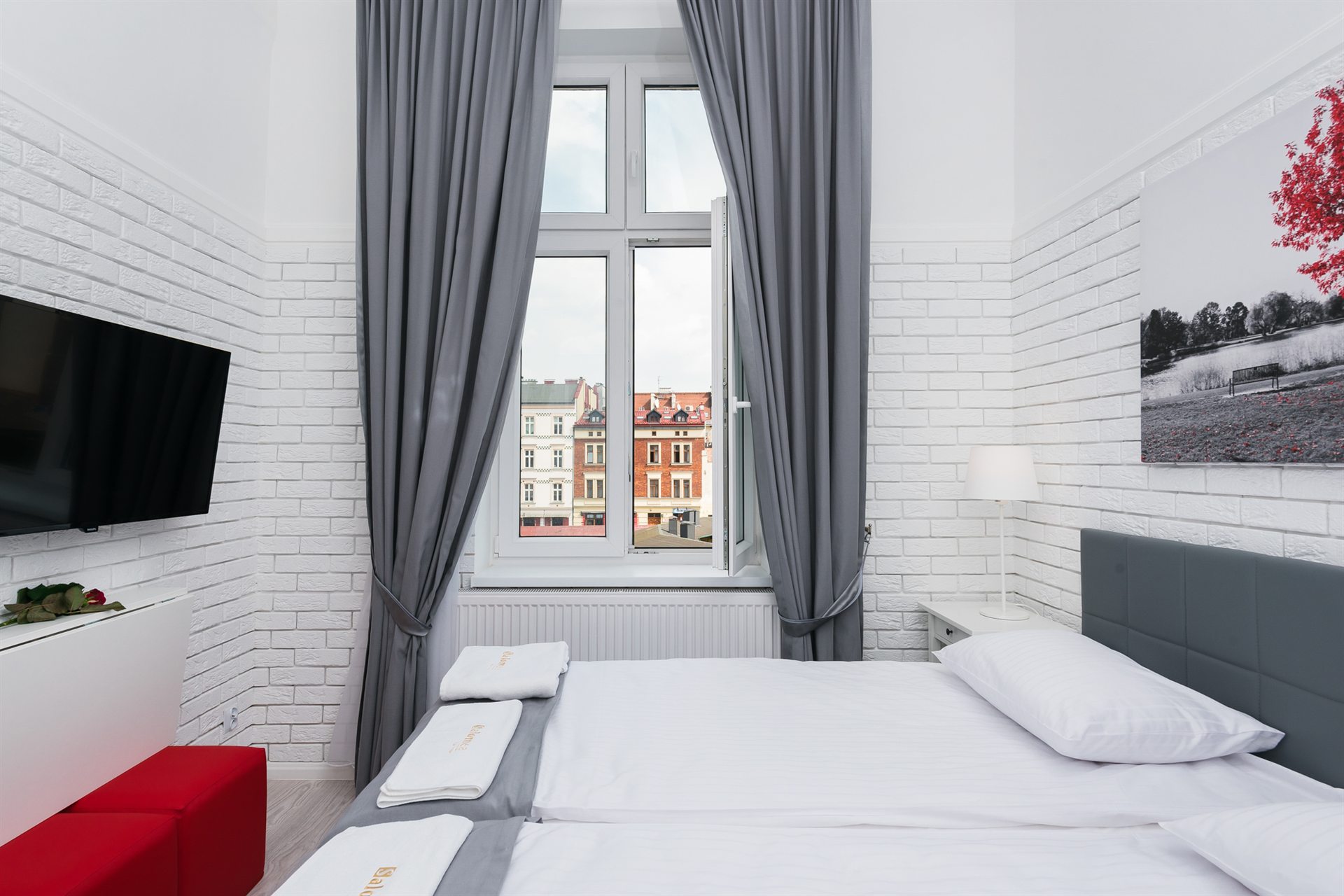 Nowoczesna sypialnia z szarymi zasłonami i białą cegłą, widok na miasto